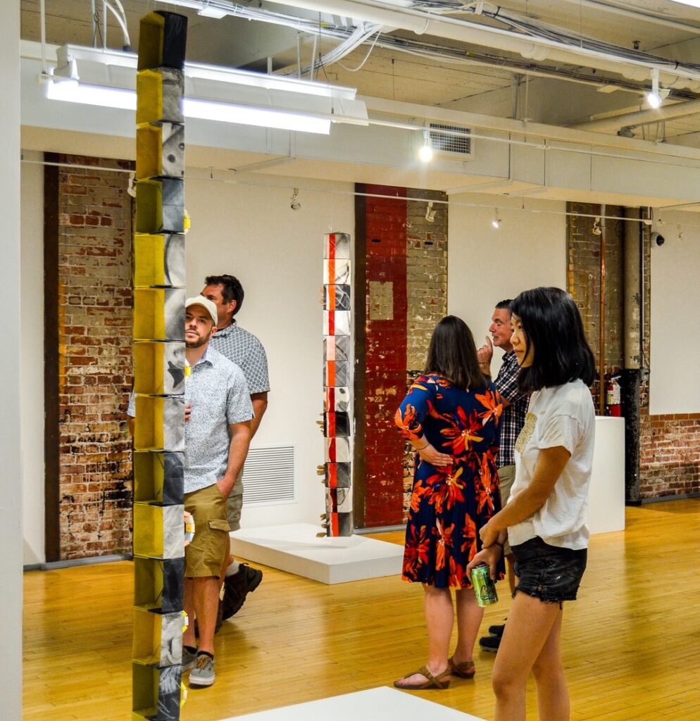 A gallery view with visitors looking at sculptures on display by artist Joanna White.