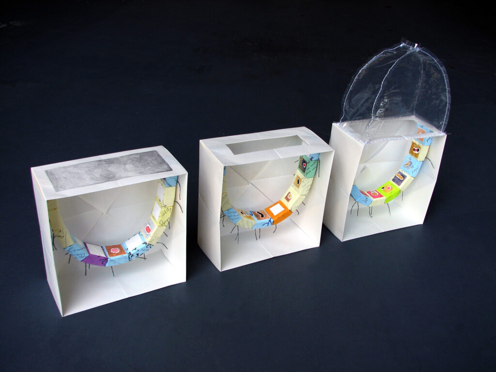 Three white paper boxes in a row with an arc of colorful painted post-it note boxes inside, and a clear plastic dome on the top of the last box.