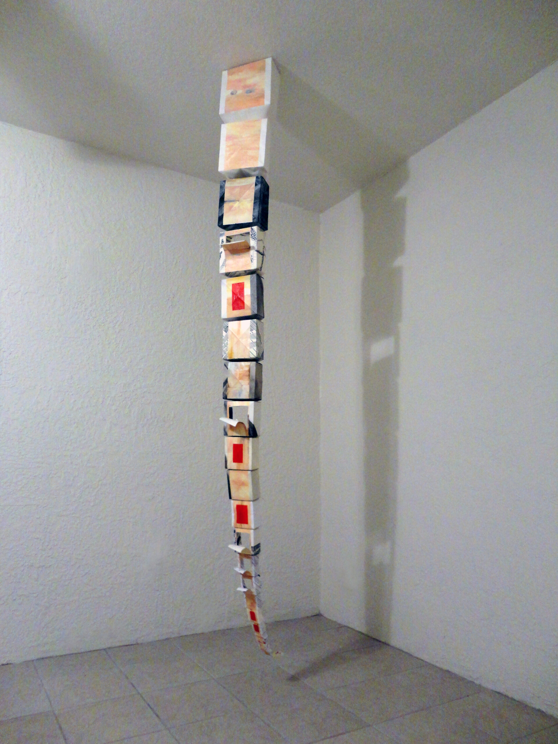 A long, tapered paper sculpture hung vertically from the ceiling by artist Joanna White.
