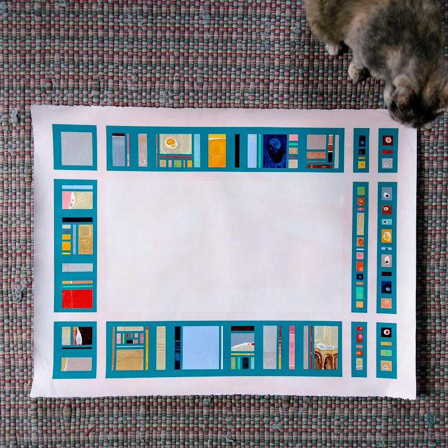A geometric oil painting sitting on a rug with a gray cat next to it.